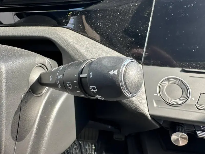 Gros plan sur la commande des essuie-glaces à gauche du volant dans l’habitacle noir du Peugeot 308 bleu 2025.