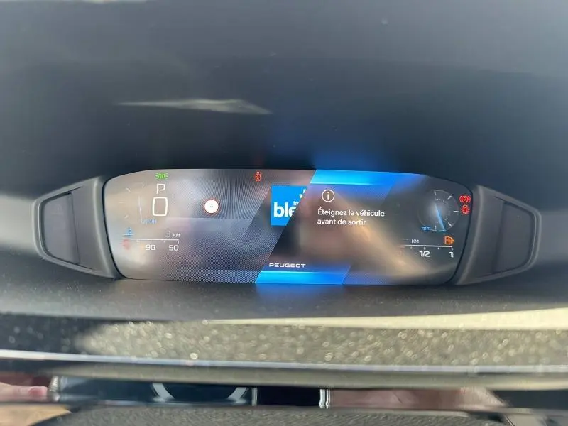 Affichage numérique du tableau de bord de la Peugeot 308 bleu, avec message d'arrêt du véhicule visible de face.