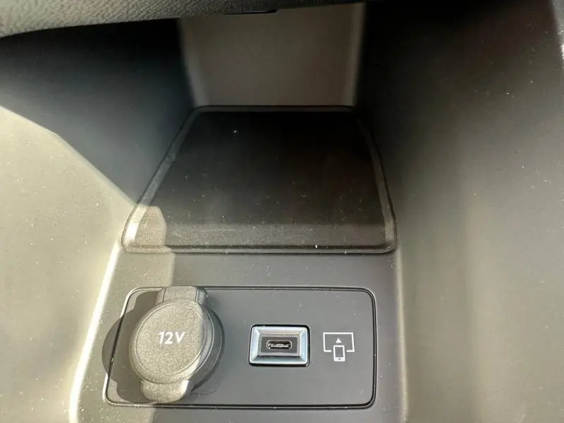 Prise 12V et port USB-C vus en gros plan dans l’habitacle d’une Peugeot 308 bleu, console centrale.
