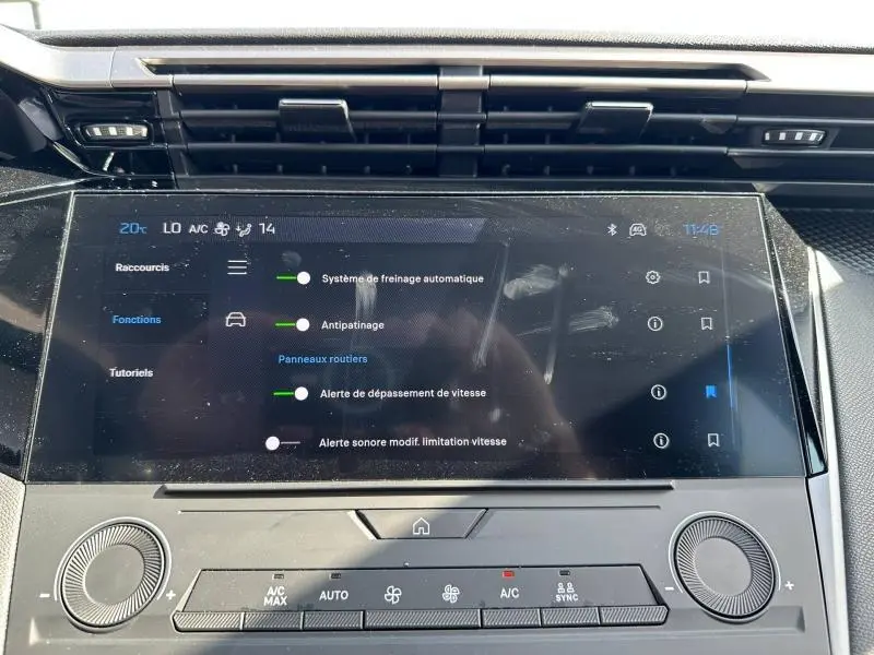 Écran tactile central de la Peugeot 308 bleu, vue rapprochée du tableau de bord avec commandes climatisation.