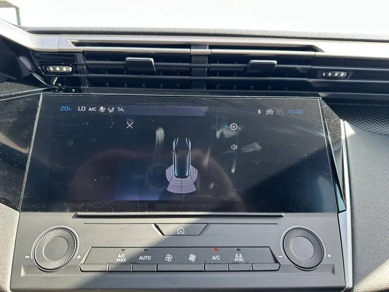 Vue rapprochée de l'écran tactile central du tableau de bord de la Peugeot 308 bleu, affichant l'aide au stationnement.