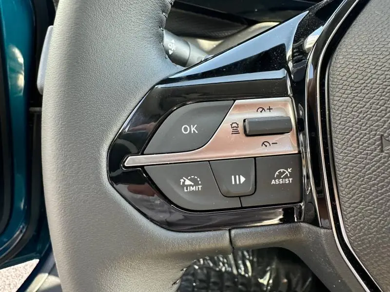 Gros plan sur les commandes multifonctions à gauche du volant d’une Peugeot 308 bleu Obsession 2025.
