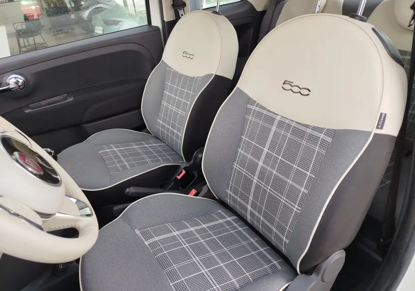 Vue intérieure côté conducteur de la Fiat 500 Lounge 2017, sièges gris à motif carreaux avec appuie-tête crème brodé 500.