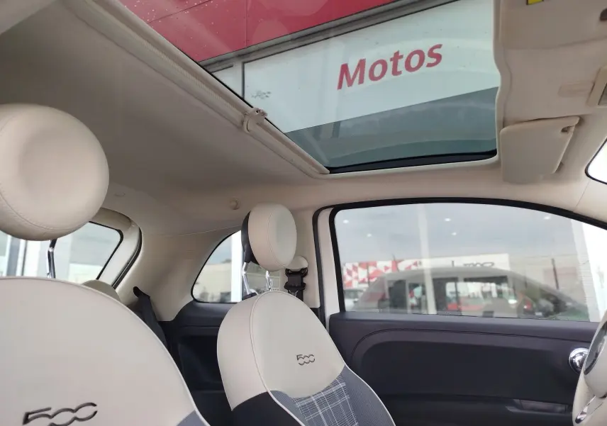 Vue intérieure côté droit de la Fiat 500 Lounge blanche, avec toit ouvrant et sièges avant en cuir clair brodés 500.