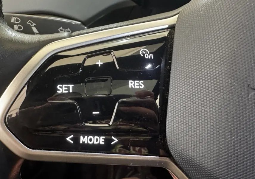 Gros plan sur les commandes du régulateur de vitesse au volant du Volkswagen ID.4 blanc, version 77 kWh Pro Performance.