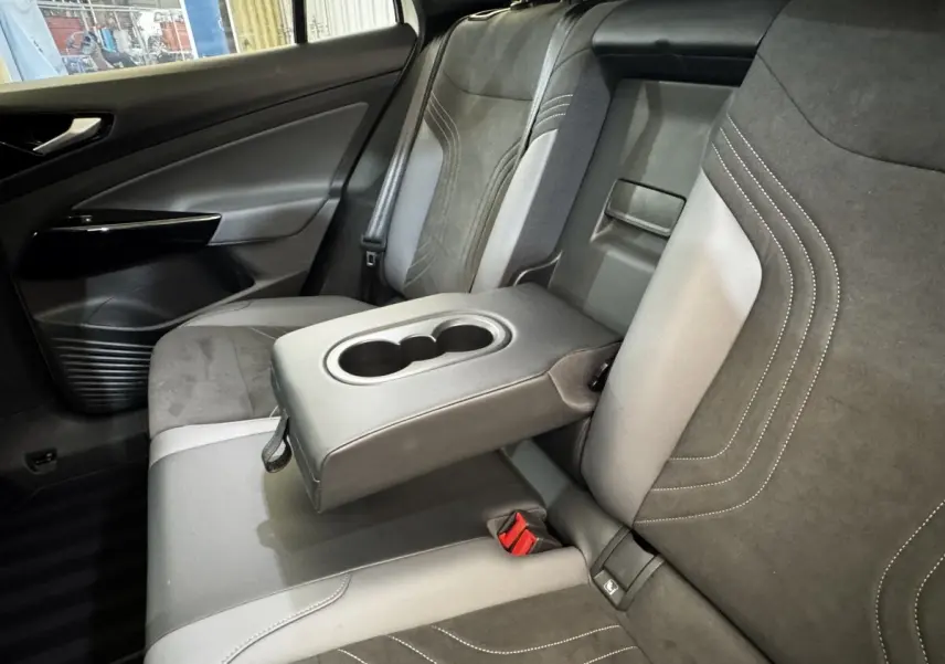 Vue intérieure côté gauche de la banquette arrière grise et noire du Volkswagen ID.4 avec accoudoir central relevé et porte-gobelets.