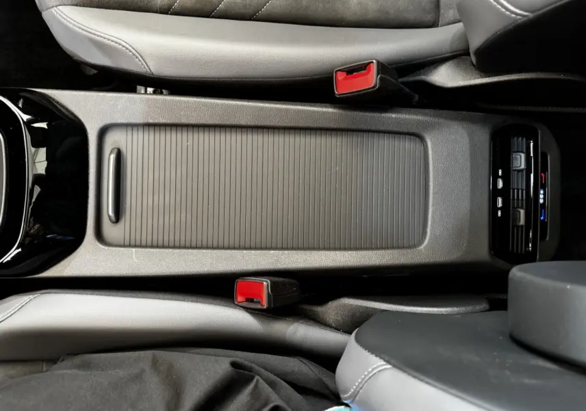 Vue plongeante sur la console centrale noire du Volkswagen ID.4 blanc, avec ceintures rouges et commandes climatisation arrière.