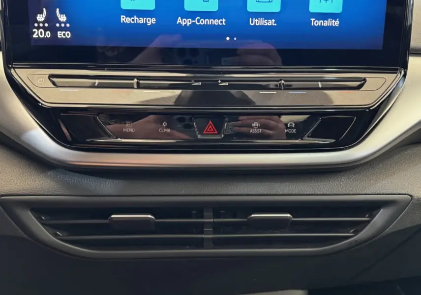 Gros plan sur la console centrale noire du Volkswagen ID.4 avec écran tactile et commandes tactiles sous l'écran.