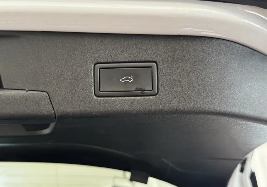 Gros plan sur le bouton d'ouverture électrique du coffre, intérieur noir du hayon du Volkswagen ID.4 blanc.