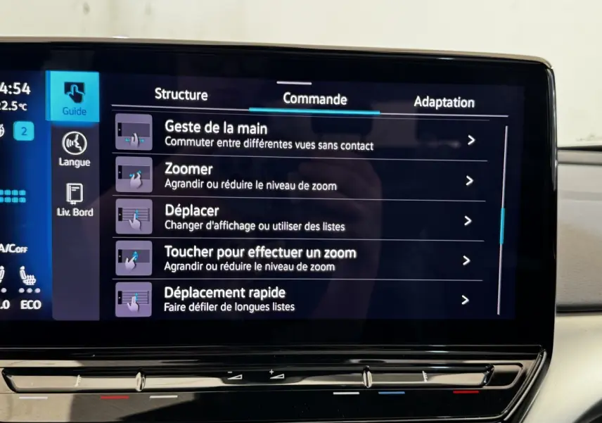 Vue de face intérieure du tableau de bord du Volkswagen ID.4 blanc avec écran tactile affichant les commandes de zoom et déplacement.