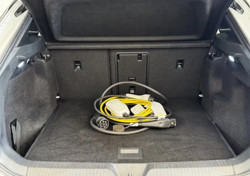 Coffre ouvert d’un Volkswagen ID.4 blanc, vue intérieure montrant un câble de recharge électrique jaune et noir.