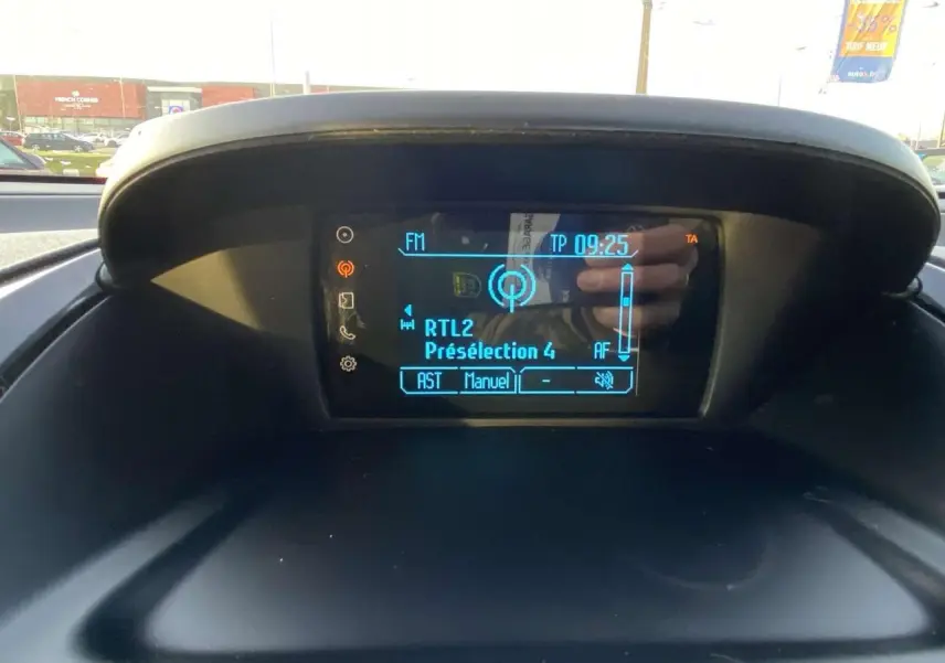 Écran central du tableau de bord de la Ford B-MAX 2014 affichant la radio FM RTL2 en extérieur lumineux.