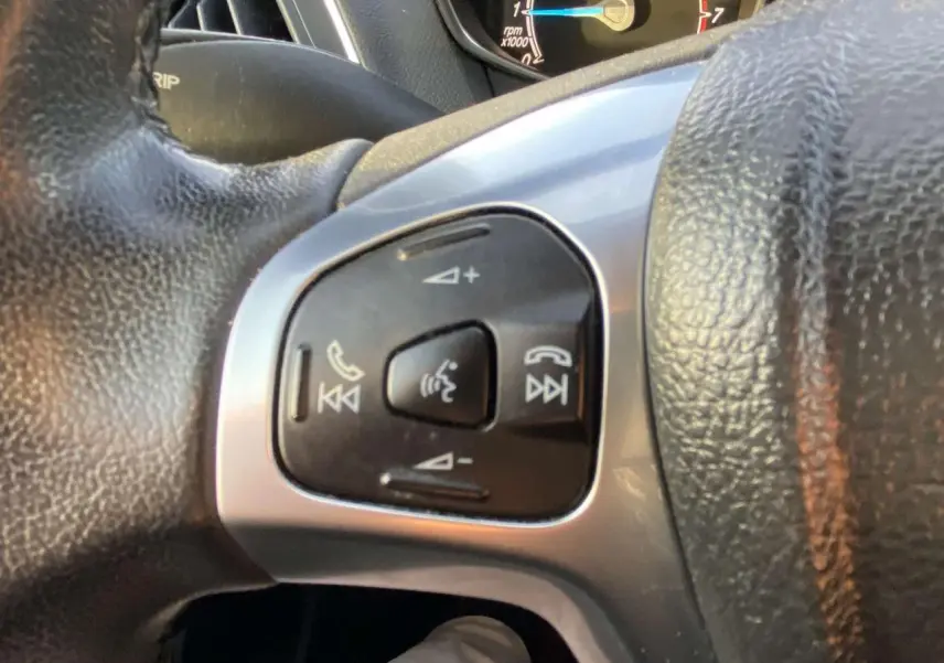 Gros plan sur les commandes vocales et téléphoniques au volant d’une Ford B-MAX blanche de 2014.