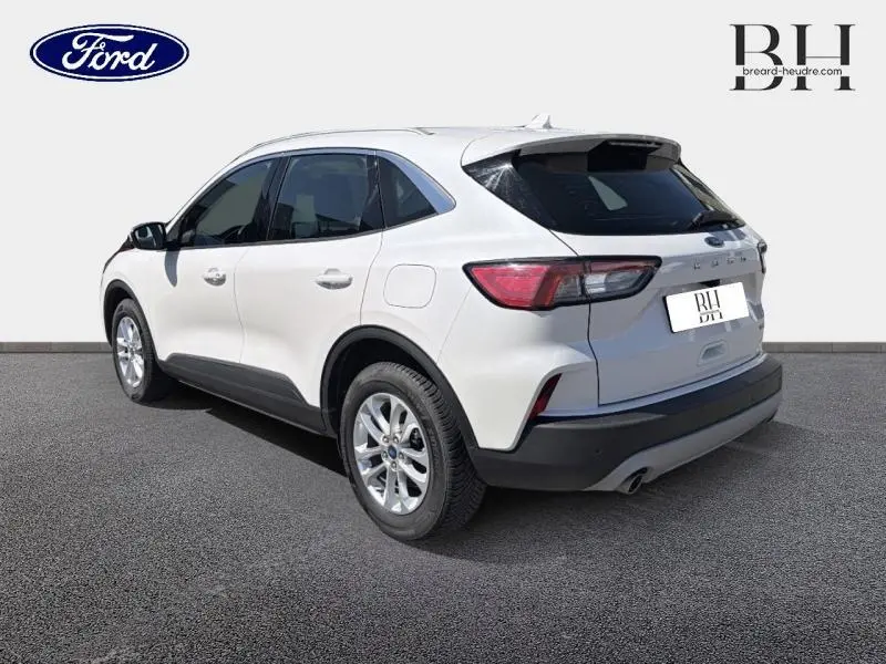 Vue 3/4 arrière droite d'un Ford Kuga blanc Glacier 2023 avec jantes alu et barres de toit noires.