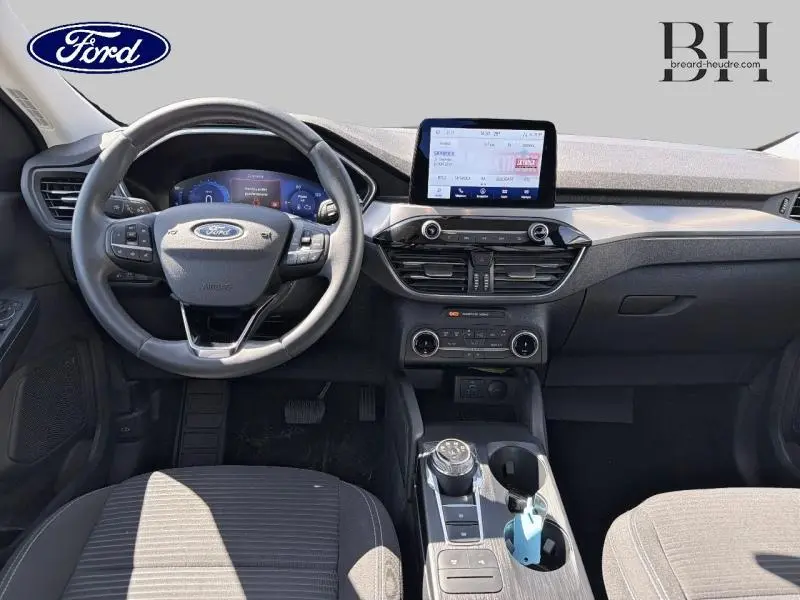Vue intérieure avant du Ford Kuga 2023 montrant le volant cuir multifonction et l'écran tactile central.
