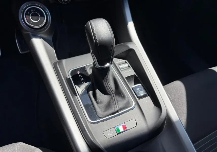 Gros plan sur la console centrale de l'Alfa Romeo Tonale blanche, avec levier de boîte auto et détail du drapeau italien.