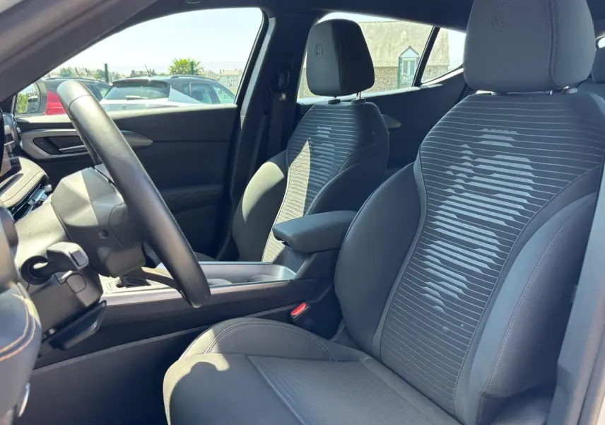Vue intérieure côté conducteur de l'Alfa Romeo Tonale 2025, sièges noirs avec motif rayé et accoudoir central.