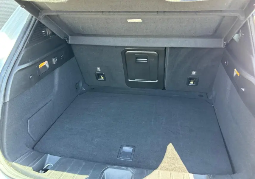 Vue intérieure du coffre spacieux de l'Alfa Romeo Tonale 1.5 Hybrid 130 Sprint TCT, revêtement noir et trappe à skis centrale.