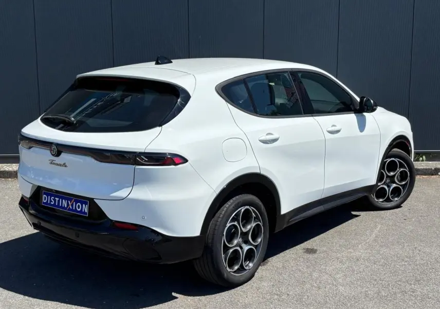 Vue 3/4 arrière droite d'un Alfa Romeo Tonale blanc métallisé avec jantes alliage 18 pouces et feux arrière full LED.
