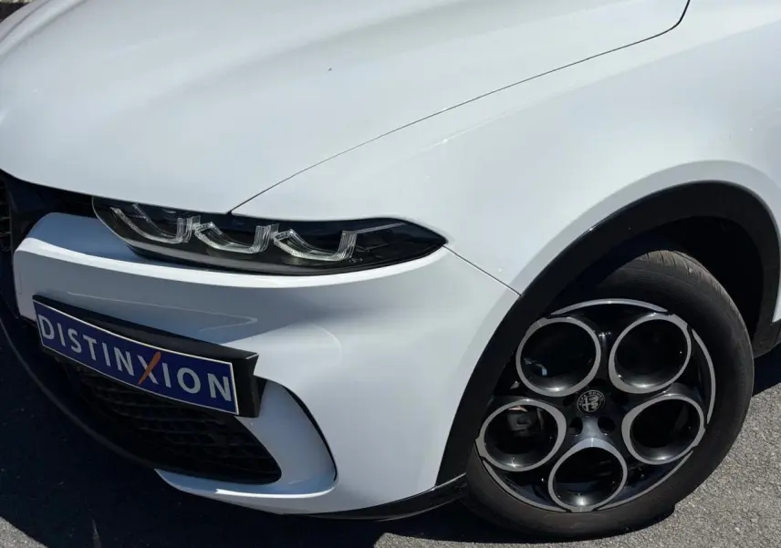 Vue 3/4 avant droit de l'Alfa Romeo Tonale blanc métallisé, mettant en valeur ses phares Full-LED et jantes alliage 18 pouces.