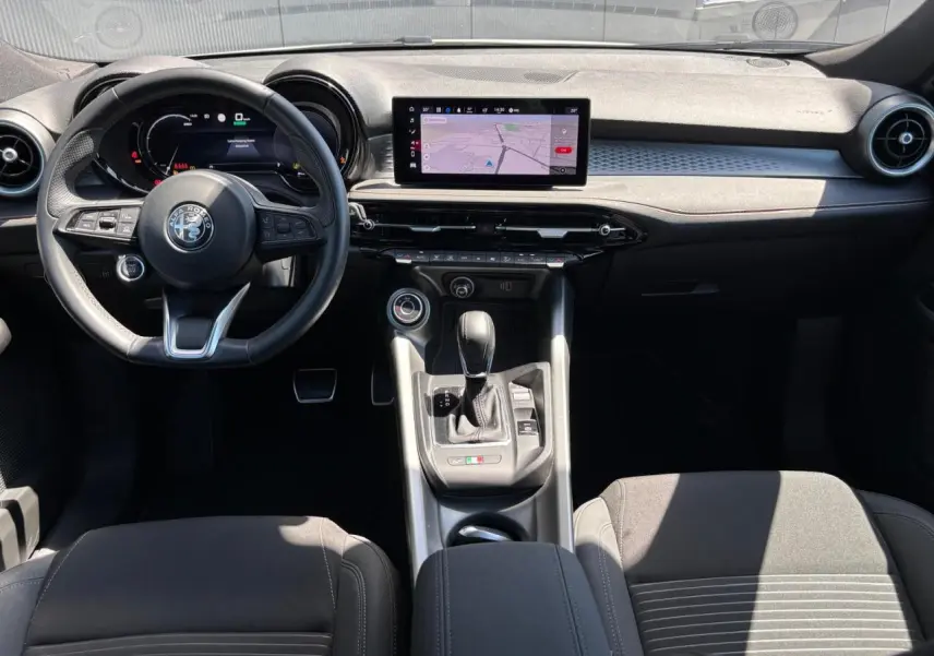 Vue intérieure avant de l'Alfa Romeo Tonale 2025 avec tableau de bord digital et volant sport en cuir noir.