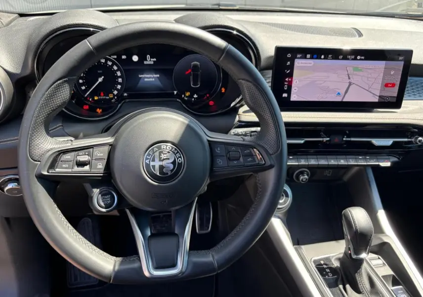 Vue intérieure centrée sur le volant cuir noir et le tableau de bord digital de l'Alfa Romeo Tonale 2025.