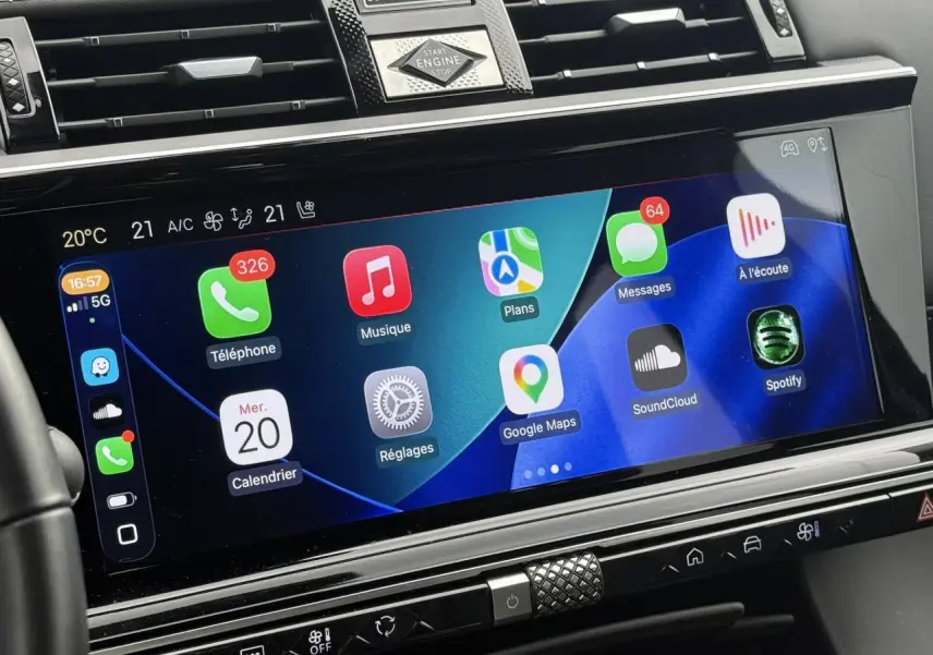 Gros plan sur l'écran tactile central du DS7 2025, affichant Apple CarPlay avec icônes colorées et commandes climatisation.