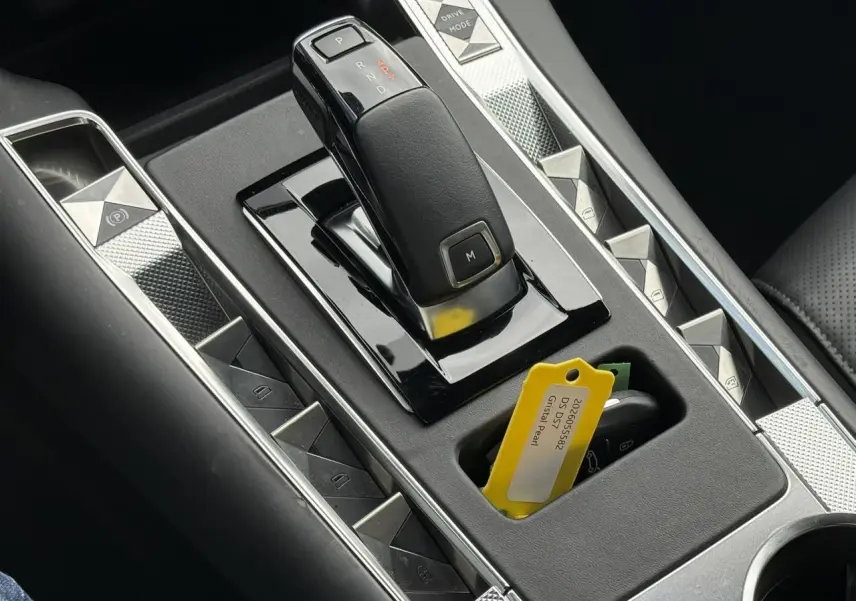 Gros plan sur la console centrale noire du DS7 1.5 BlueHDI avec levier de vitesses automatique et clé avec étiquette jaune Cristal Pearl.