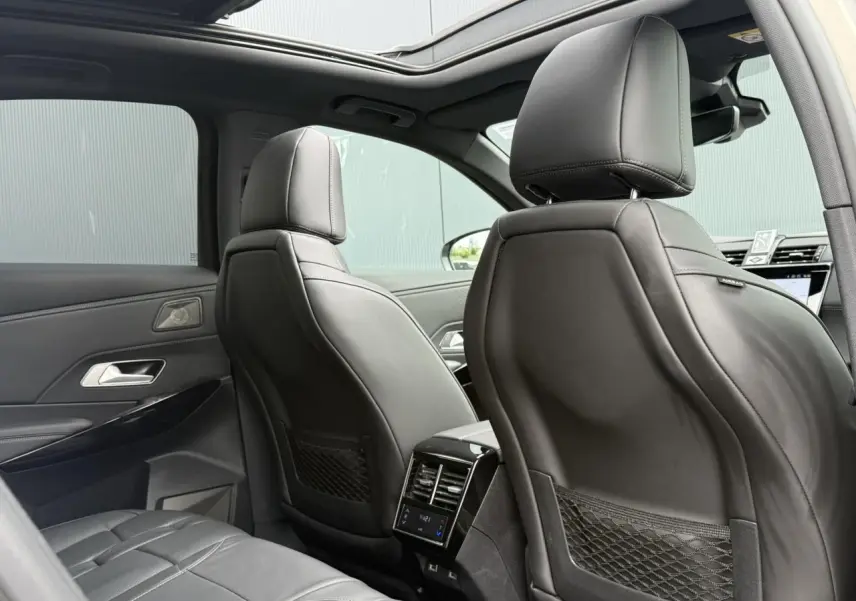 Vue intérieure arrière du DS7 2025 avec sièges en cuir noir Basalte et toit ouvrant panoramique ouvert.