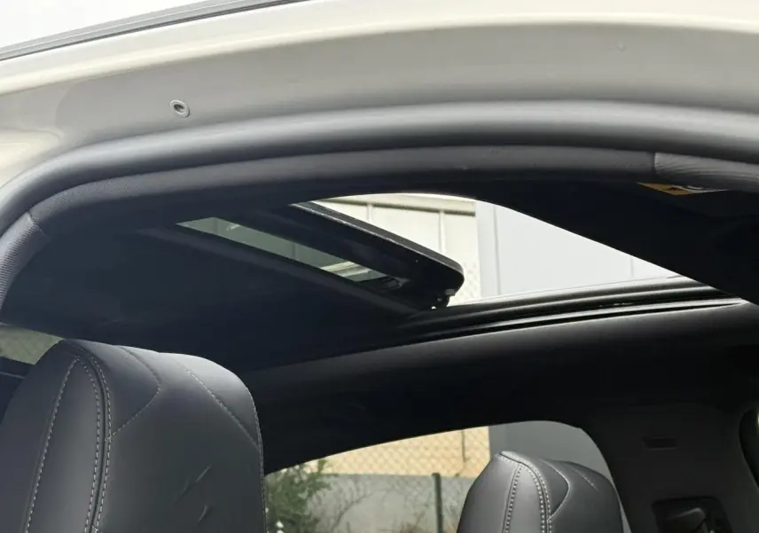 Vue intérieure du toit ouvrant panoramique ouvert du DS7 Cristal Pearl, avec sièges avant en cuir noir visibles.