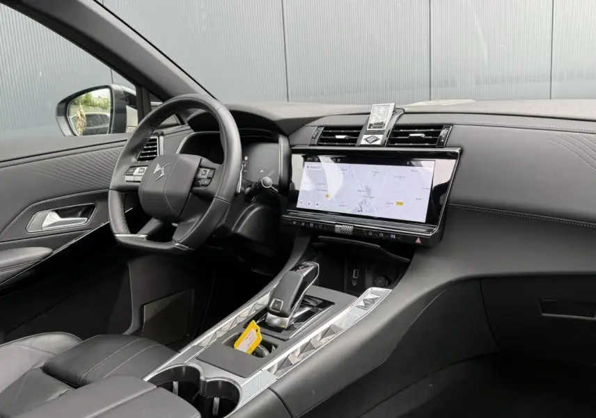 Vue intérieure côté conducteur du DS7 2025 avec tableau de bord noir, écran tactile et console centrale moderne.