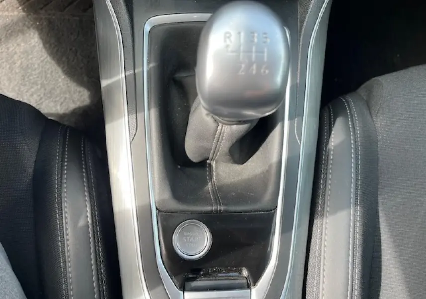 Vue rapprochée du levier de vitesse manuel et bouton start/stop de la Peugeot 308 gris clair, intérieur noir.
