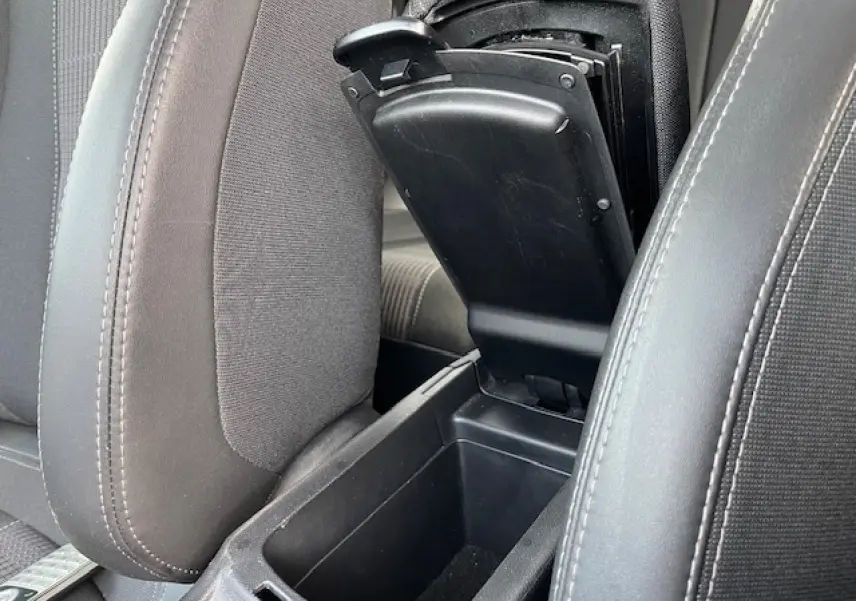 Gros plan sur l'accoudoir central avant ouvert entre les sièges avant gris foncé de la Peugeot 308 2018.