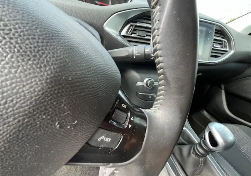 Vue rapprochée du volant et levier de vitesses manuel dans l’habitacle gris foncé d’une Peugeot 308 2018.