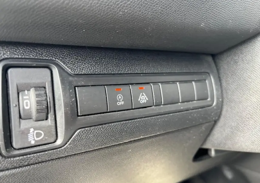 Gros plan sur les boutons de commande noirs du tableau de bord côté gauche de la Peugeot 308 gris clair.
