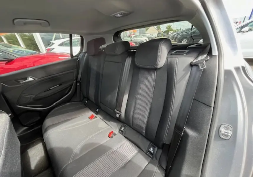 Vue intérieure arrière côté droit de la Peugeot 308 gris clair, montrant les sièges arrière en tissu noir avec ceintures de sécurité.