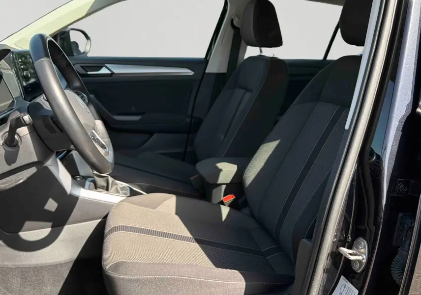 Intérieur avant droit du Volkswagen T-Roc noir 2025, sièges tissu gris et volant multifonctions visible.