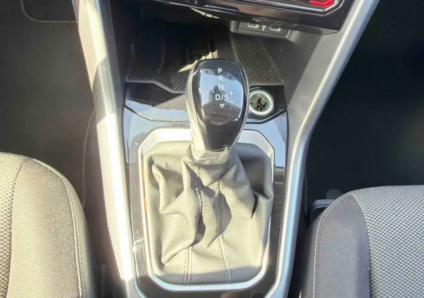 Vue rapprochée du levier de vitesse DSG7 noir entouré de cuir gris dans le Volkswagen T-Roc 2025 noir.