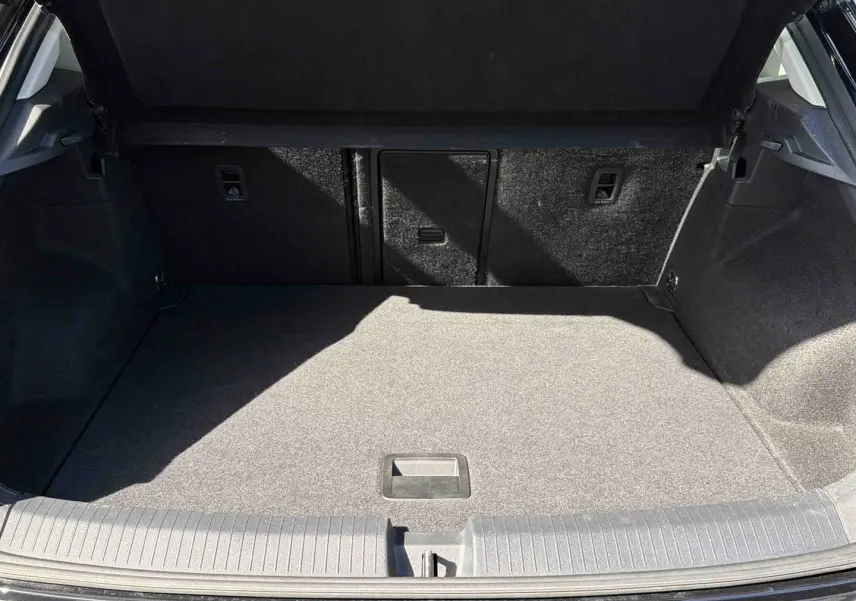 Coffre ouvert du Volkswagen T-Roc noir 2025, vue de l'arrière montrant l'espace de chargement vide et le revêtement intérieur.