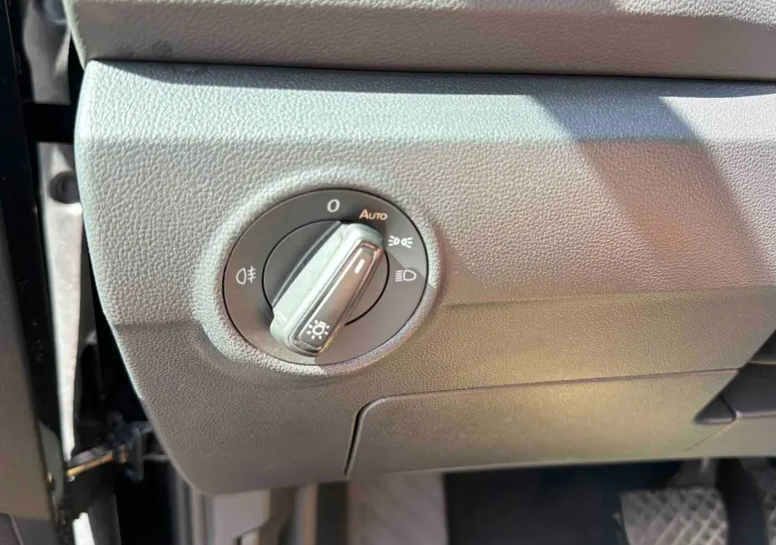 Gros plan sur le bouton de commande des phares dans l’habitacle noir du Volkswagen T-Roc 2025.