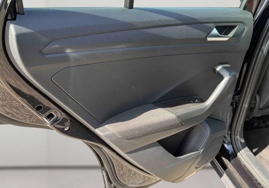 Vue intérieure de la porte arrière gauche noire du Volkswagen T-Roc 2025 avec accoudoir et commande de vitre.