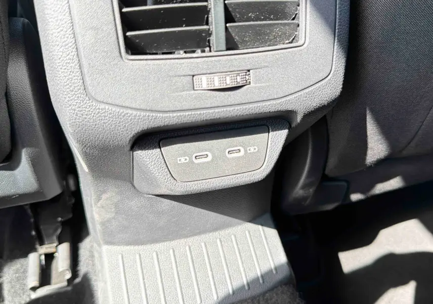 Prise USB-C double et bouche d’aération arrière dans l’habitacle du Volkswagen T-Roc noir, vue côté arrière passager.