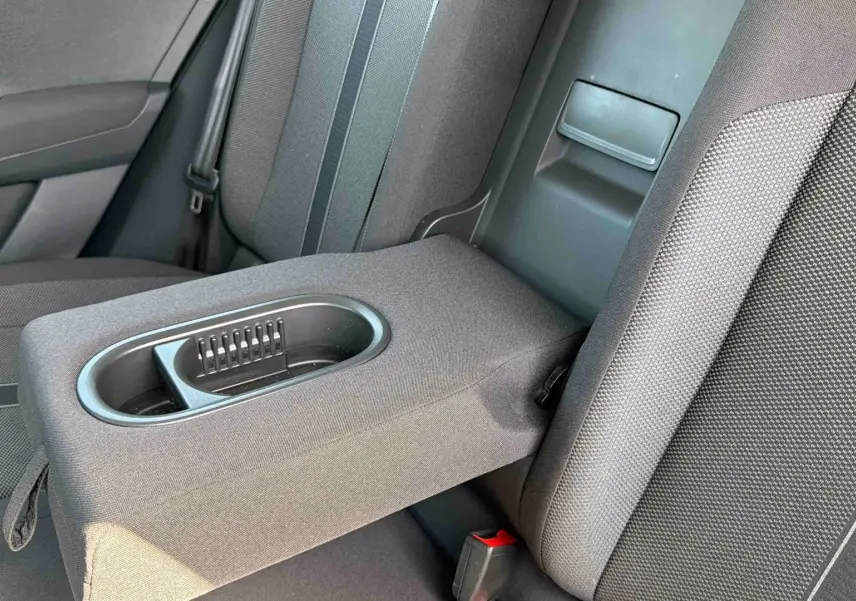 Vue rapprochée de l'accoudoir arrière avec porte-gobelets du Volkswagen T-Roc noir, intérieur tissu gris.