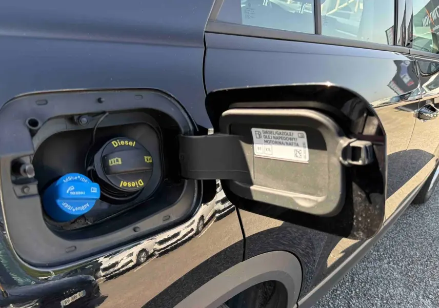 Vue rapprochée de la trappe à carburant ouverte côté gauche d’un Volkswagen T-Roc noir diesel.