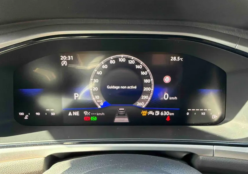 Tableau de bord digital du Volkswagen T-Roc 2025 affichant la vitesse et alertes, vu de face intérieur noir.
