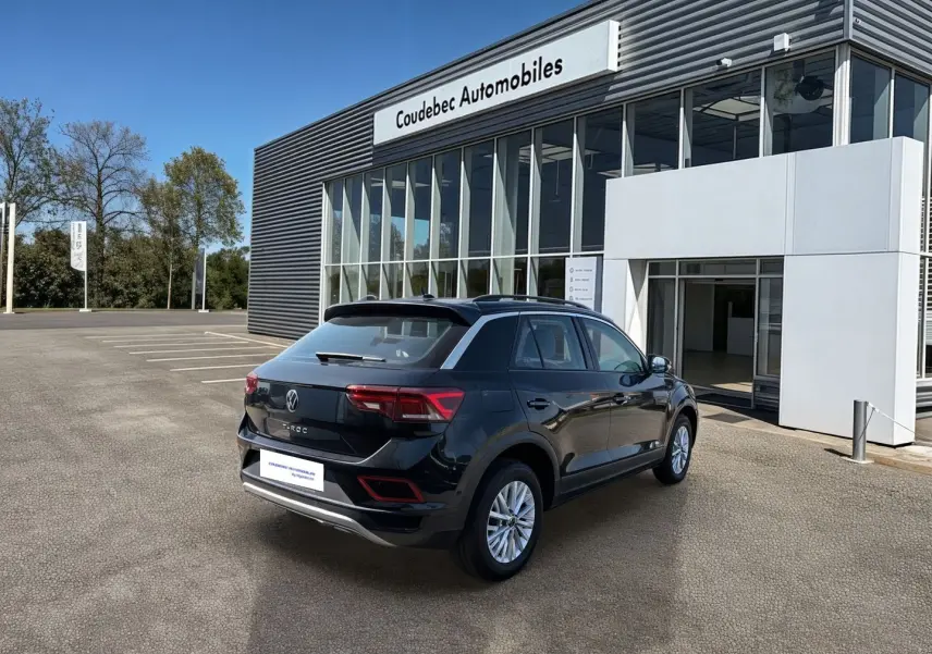 Volkswagen T-Roc noir vue 3/4 arrière droit devant concession Coudebec Automobiles par temps clair.