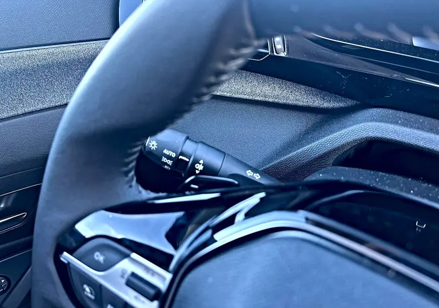 Gros plan sur le volant multifonction noir et la commande des phares à gauche dans l’habitacle d’une Peugeot 308.