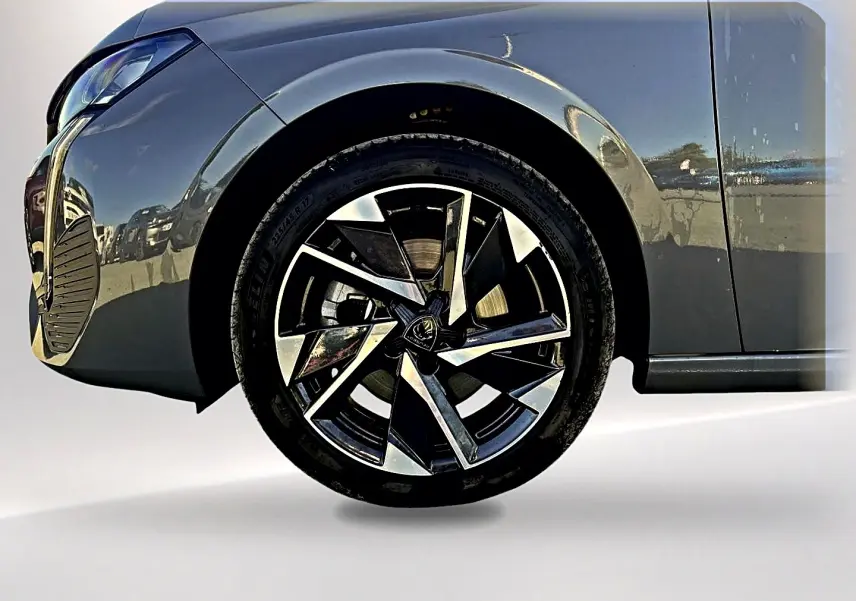 Gros plan sur la roue avant gauche et l'aile d'une Peugeot 308 gris selenium avec jante alu au design moderne.
