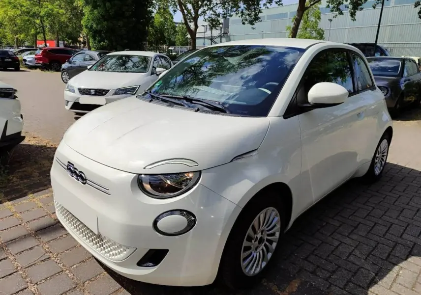 Fiat 500 électrique blanche vue 3/4 avant droit, avec phares ronds et calandre épurée distinctive.