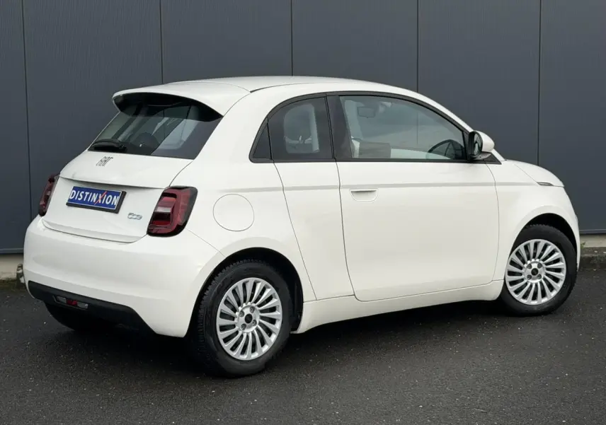 Vue 3/4 arrière droite d'une FIAT 500 électrique blanche avec porte arrière 3+1 distinctive et jantes multibranches.